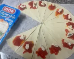 Step <p>En cada triangulo, colocaremos una cucharadita de pimientos caramelizados y un poco de gorgonzola. Formaremos el croisant empezando a enrollar desde la parte ancha hasta la más fina. Apretaremos las dos esquinas y dejaremos formado el croisant.</p> illustration